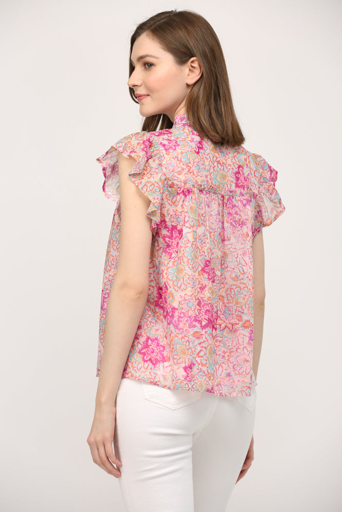 A model wearing the Aelia Floral Ruffle Top by Fate from the back, highlighting the back closure and the lightweight drape of the 100% cotton fabric.