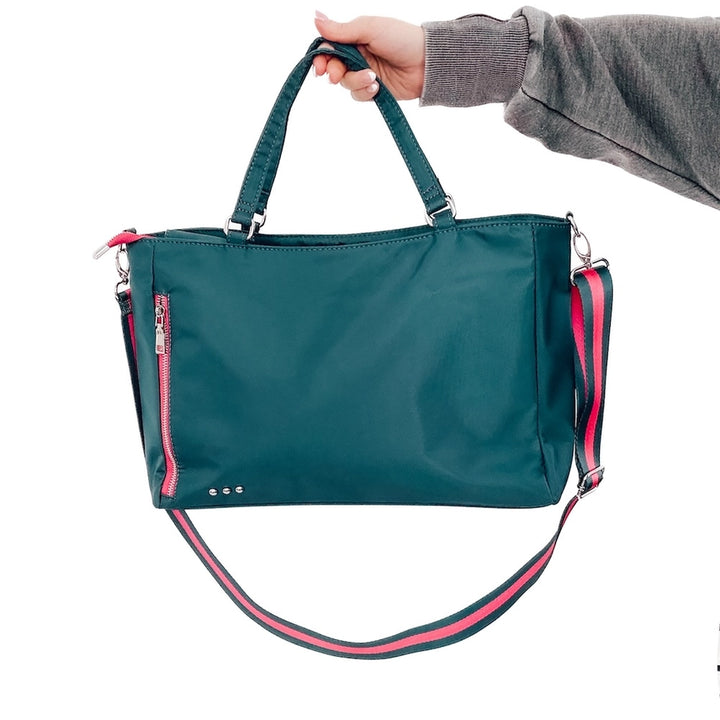 Front view holding the teal colored Nina Nylon Tote Bag with exterior zipper pocket, adjustable strap, and interior compartments for everyday convenience.