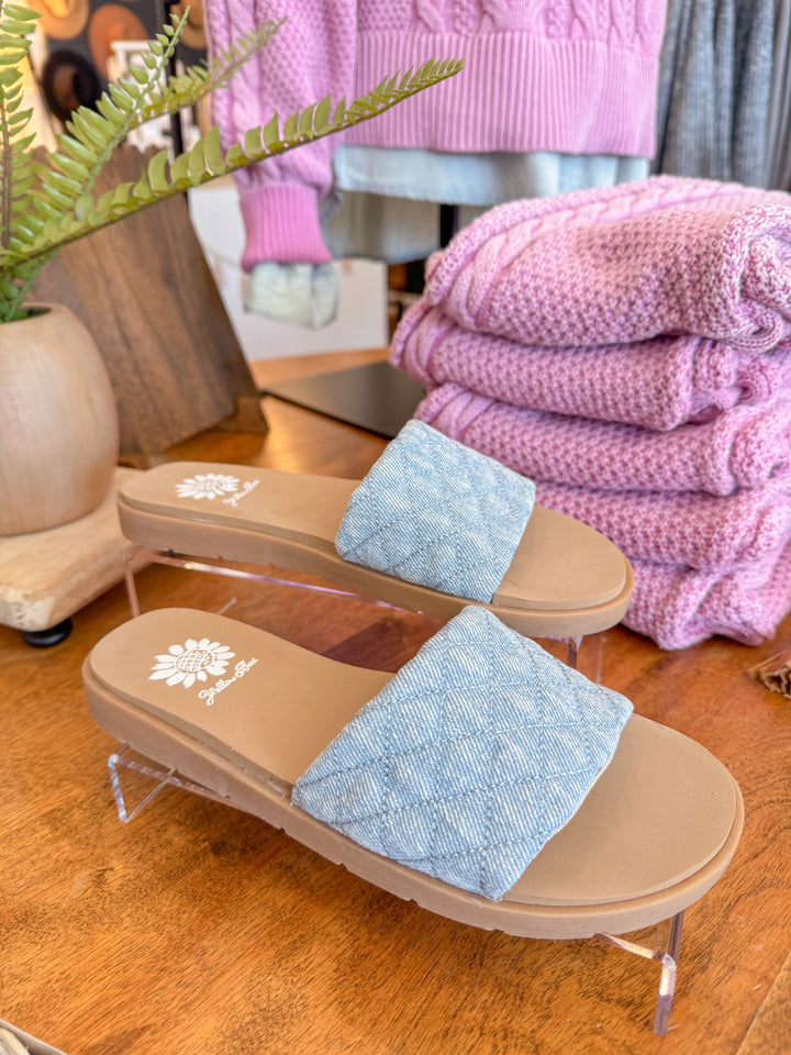 Sanibel Denim Slide Sandal with puffy quilted straps and a cushioned footbed, designed for effortless everyday wear. Light denim color.