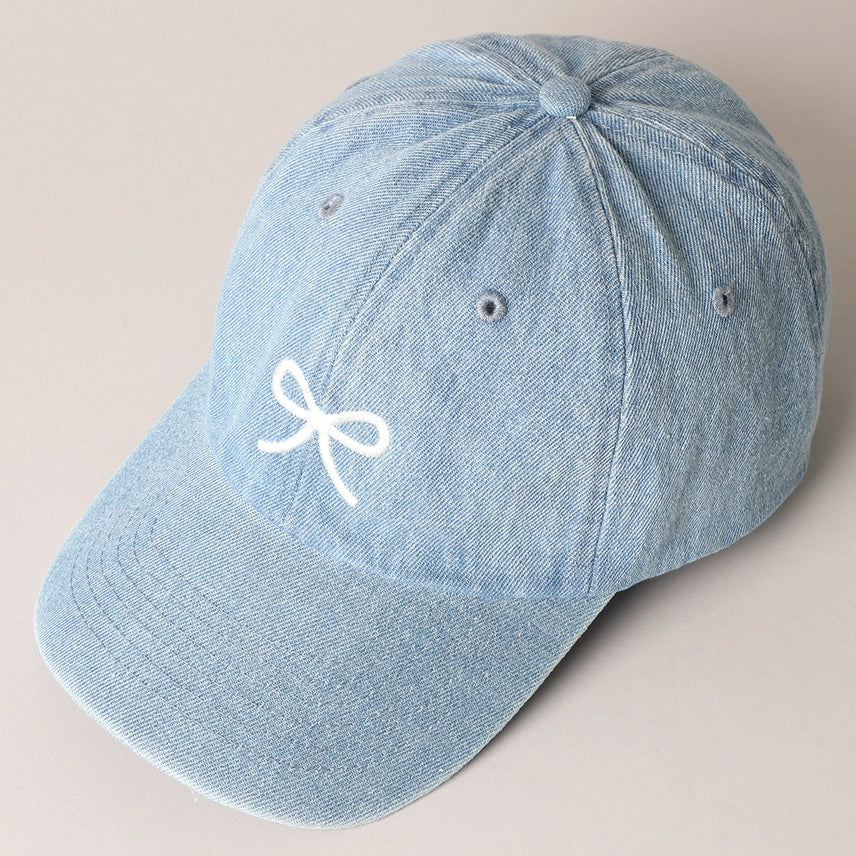 Light blue denim hat with embroidered bow and adjustable strap.
