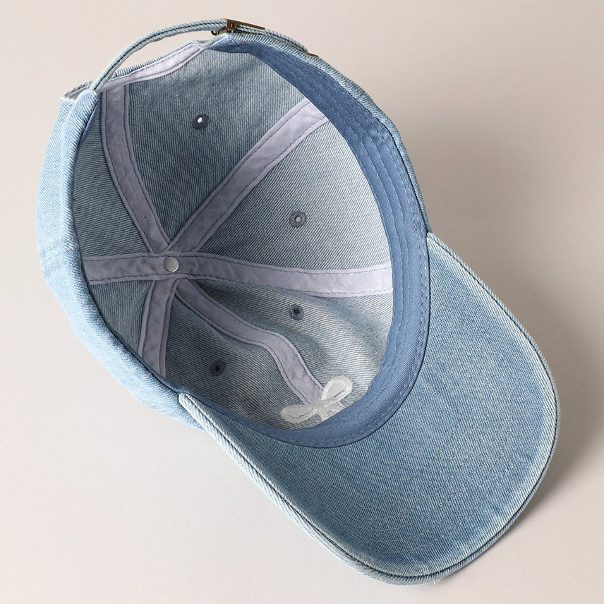 Inside look at the light blue denim hat with embroidered bow and adjustable strap.