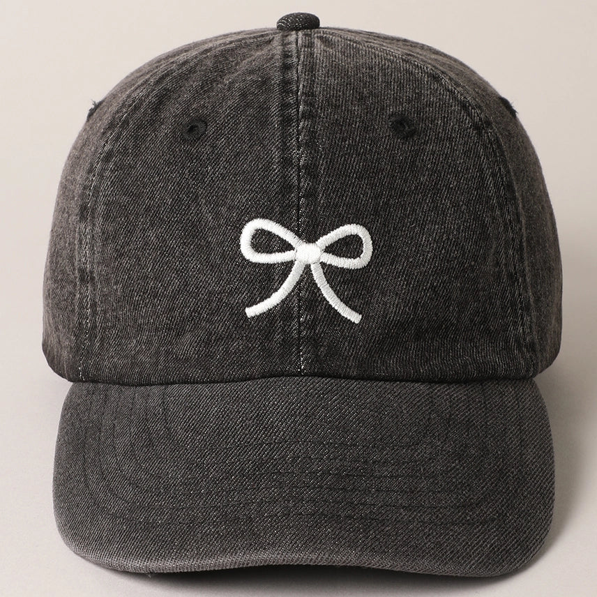 Washed black denim hat with embroidered bow and adjustable strap.