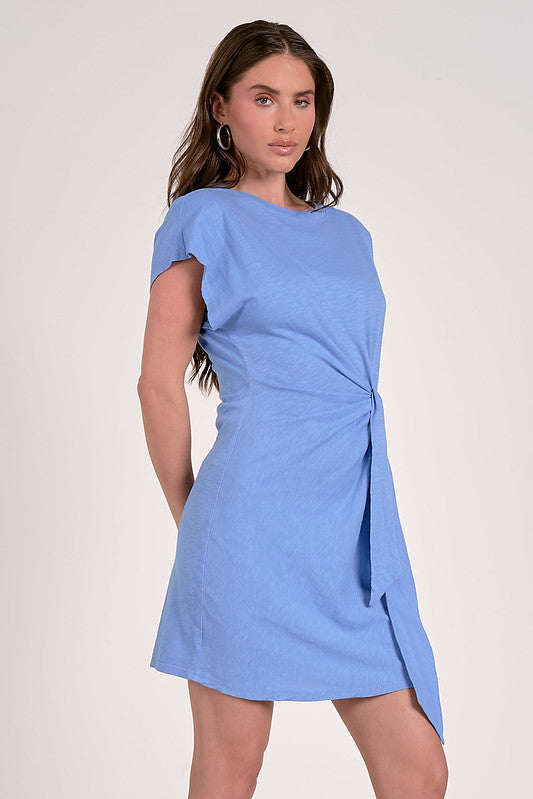 Woman wearing Elan Elle Side Tie Dress in blue – cotton wrap mini with side tie and cap sleeves.