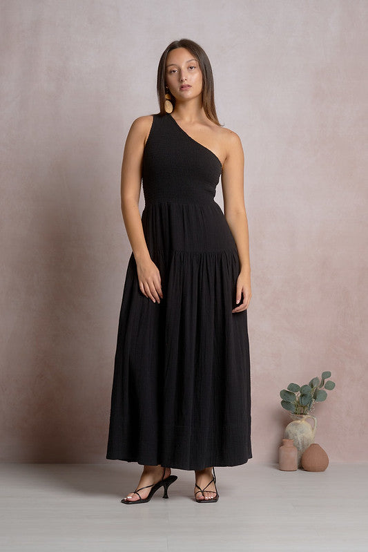 Woman wearing black one-shoulder Elan maxi dress with smocked bodice and tiered skirt