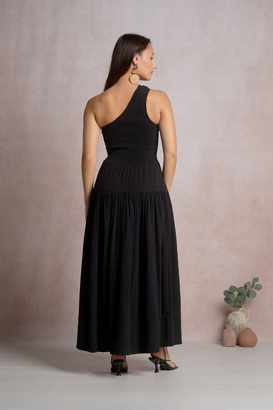 Woman wearing black one-shoulder Elan maxi dress with smocked bodice and tiered skirt