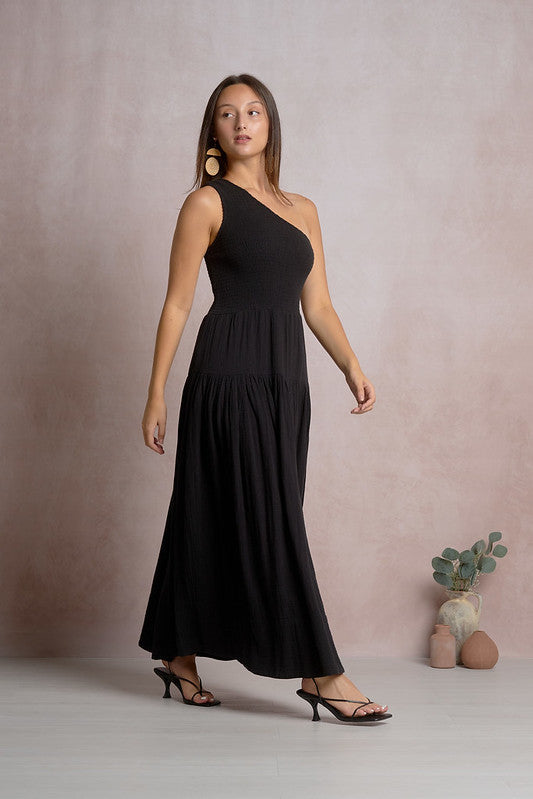Woman wearing black one-shoulder Elan maxi dress with smocked bodice and tiered skirt