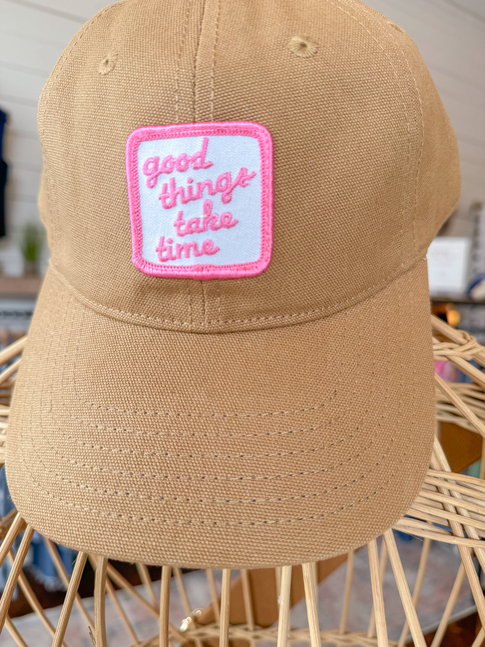 Camel colored canvas baseball cap with pink and white embroidered patch that reads "Good things take time"
