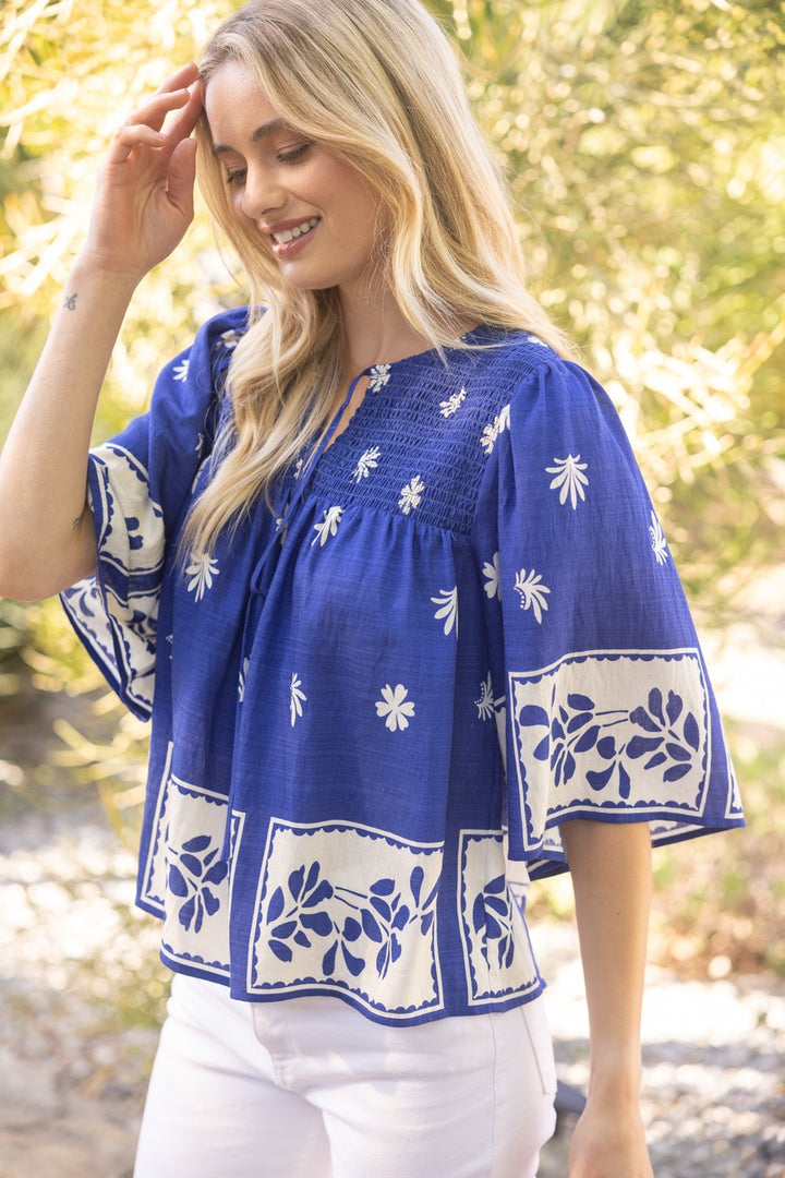 Royal blue smocked floral top with short sleeves and block print design, styled for everyday or office wear. Brand Voy.