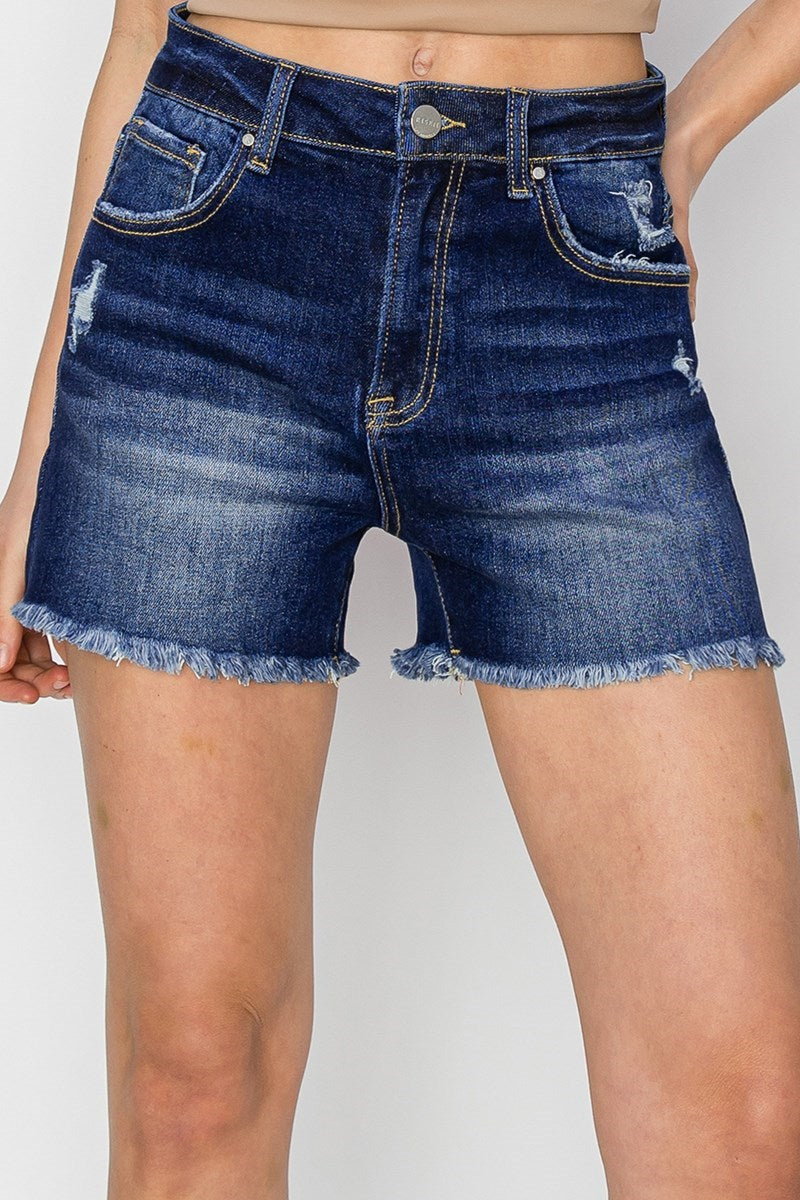 Model wearing Risen Hannah dark wash high rise denim shorts with frayed hem.