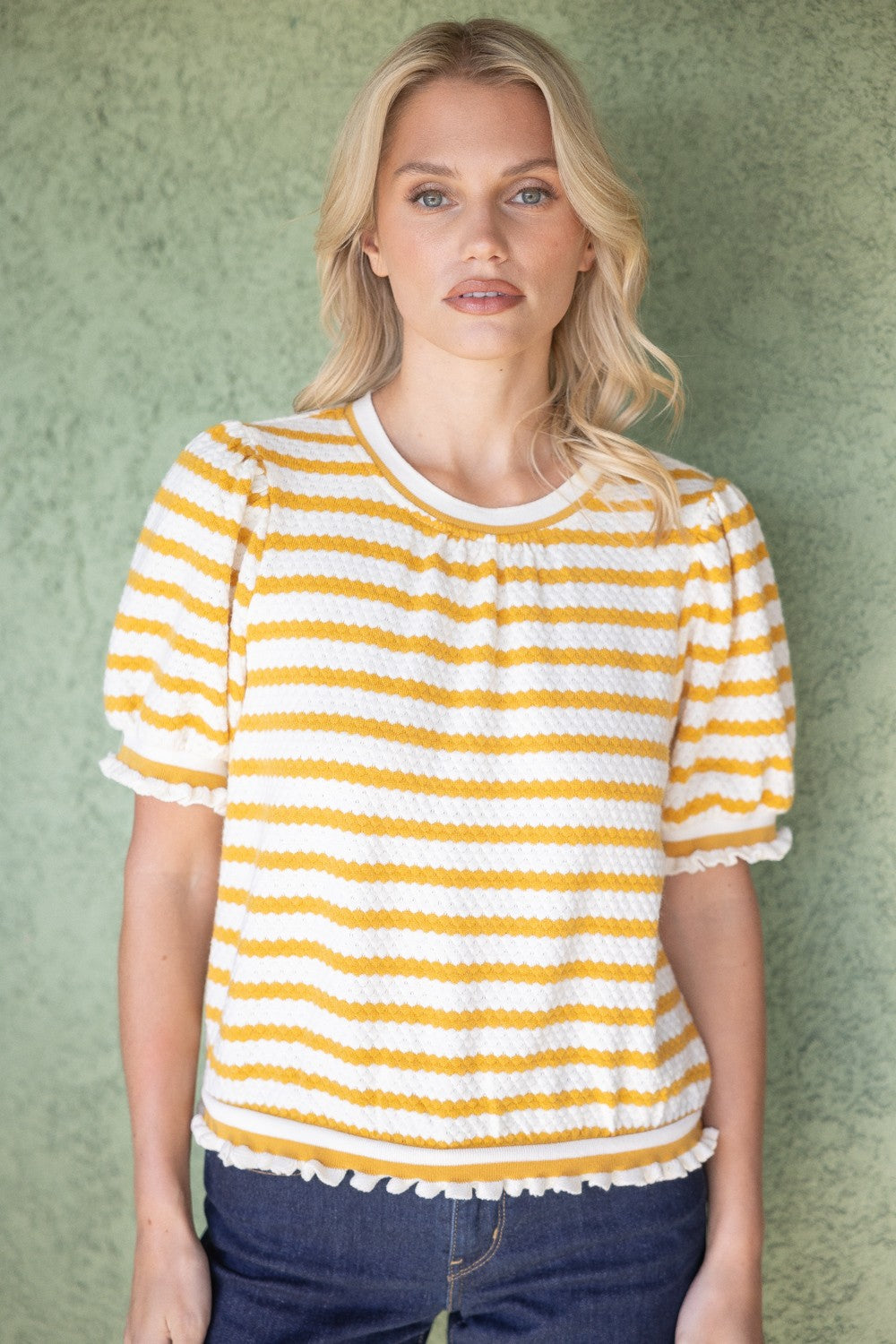 Mustard and white striped knit short sleeve blouse with ruffle trim, styled as a casual work top for women. By Voy.